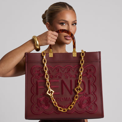 Burgundy Fendi tote bag with gold chain and tortoiseshell handles showing embossed FENDI ROMA