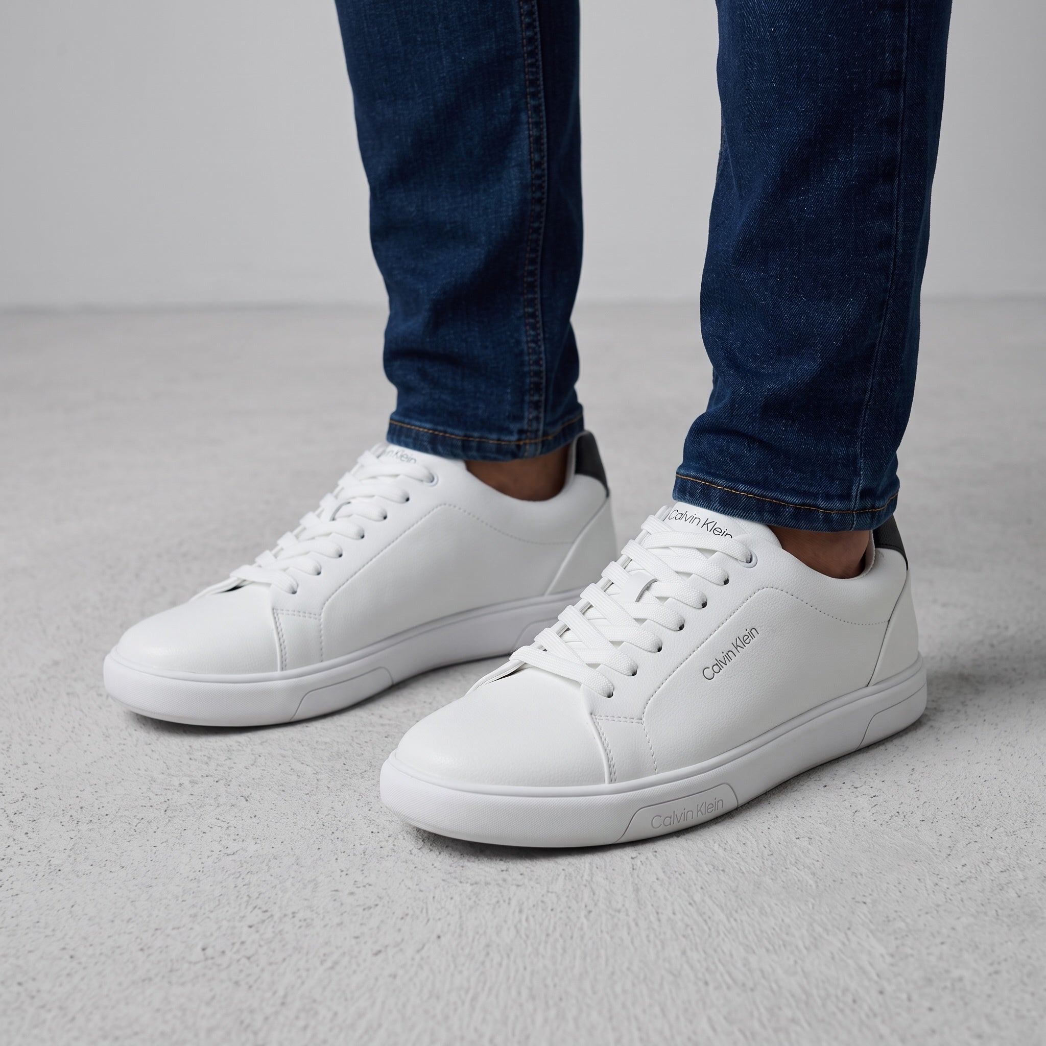 White low-top Calvin Klein sneakers with black heel tab and branded sole