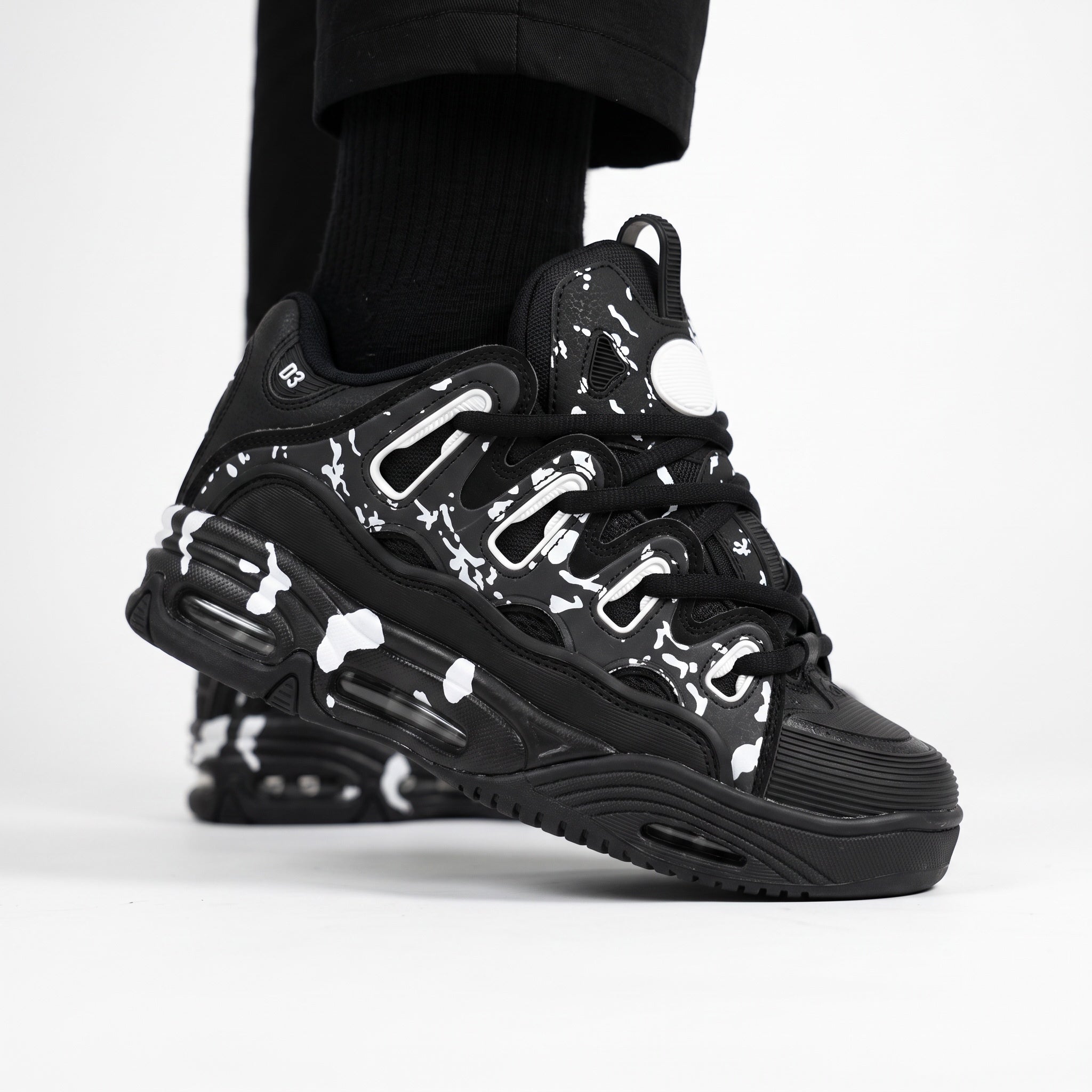 black chunky low-top sneaker with white splatter print and sculpted sole