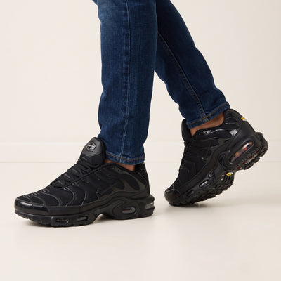 Nike Air Max Plus triple black sneakers with wavy overlays and visible Air units