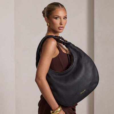 Black Schiaparelli crescent hobo shoulder bag with gold logo and eye charm on strap