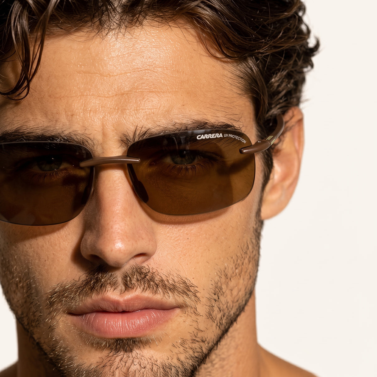 Close-up of man wearing Carrera brown sunglasses with UV protection