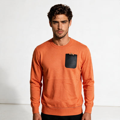 Hermès orange crewneck sweater with black embossed pouch and gold clasp on chest