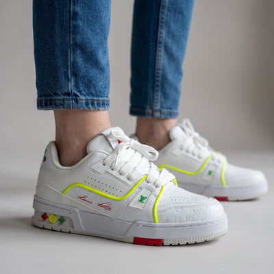 White Louis Vuitton low-top sneakers with neon yellow trim and embossed monogram