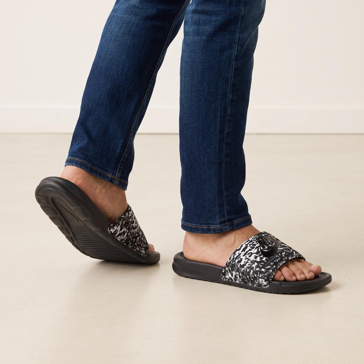 black and white speckled Nike slide sandals on model's feet