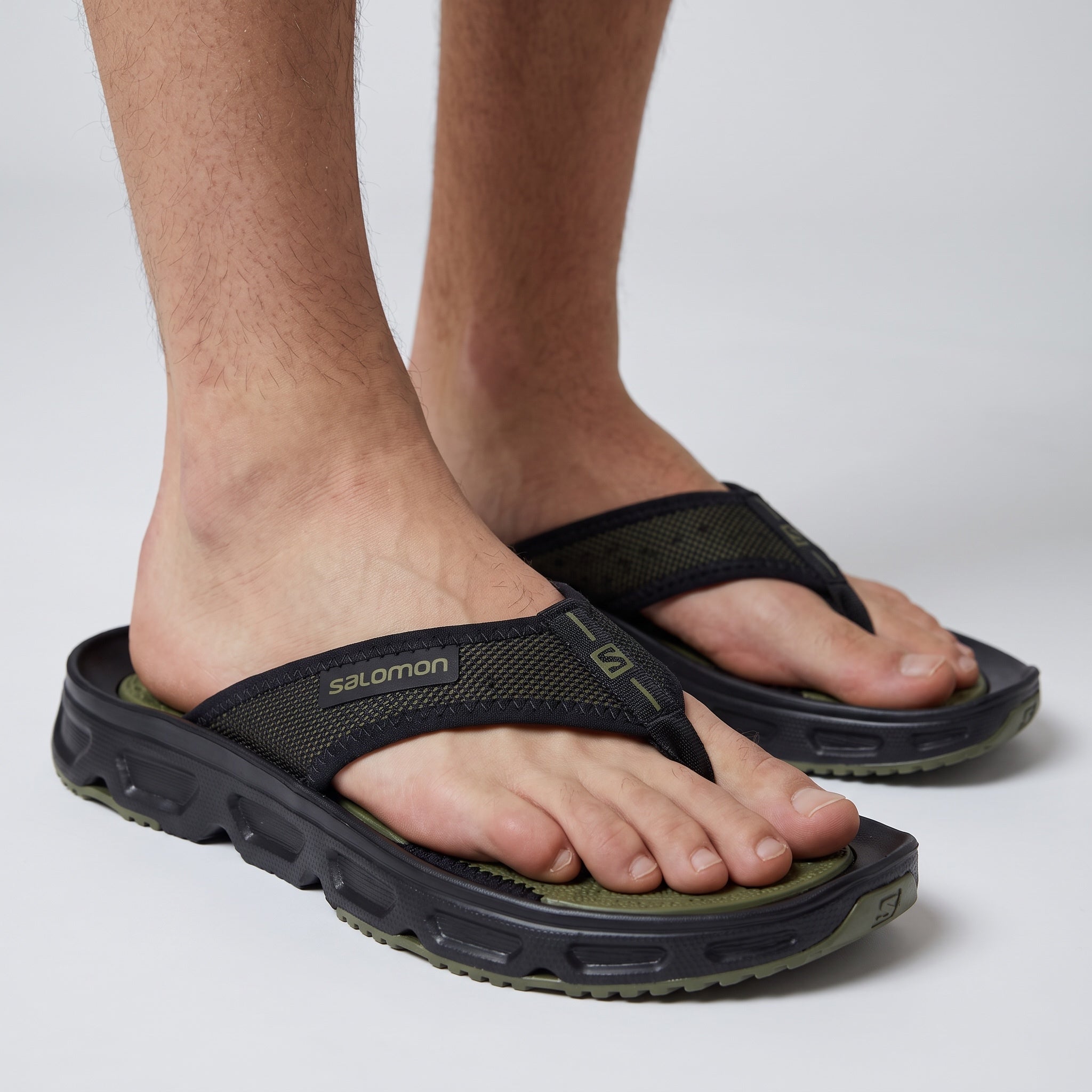 Close-up of Salomon olive and black flip-flop sandals on model feet