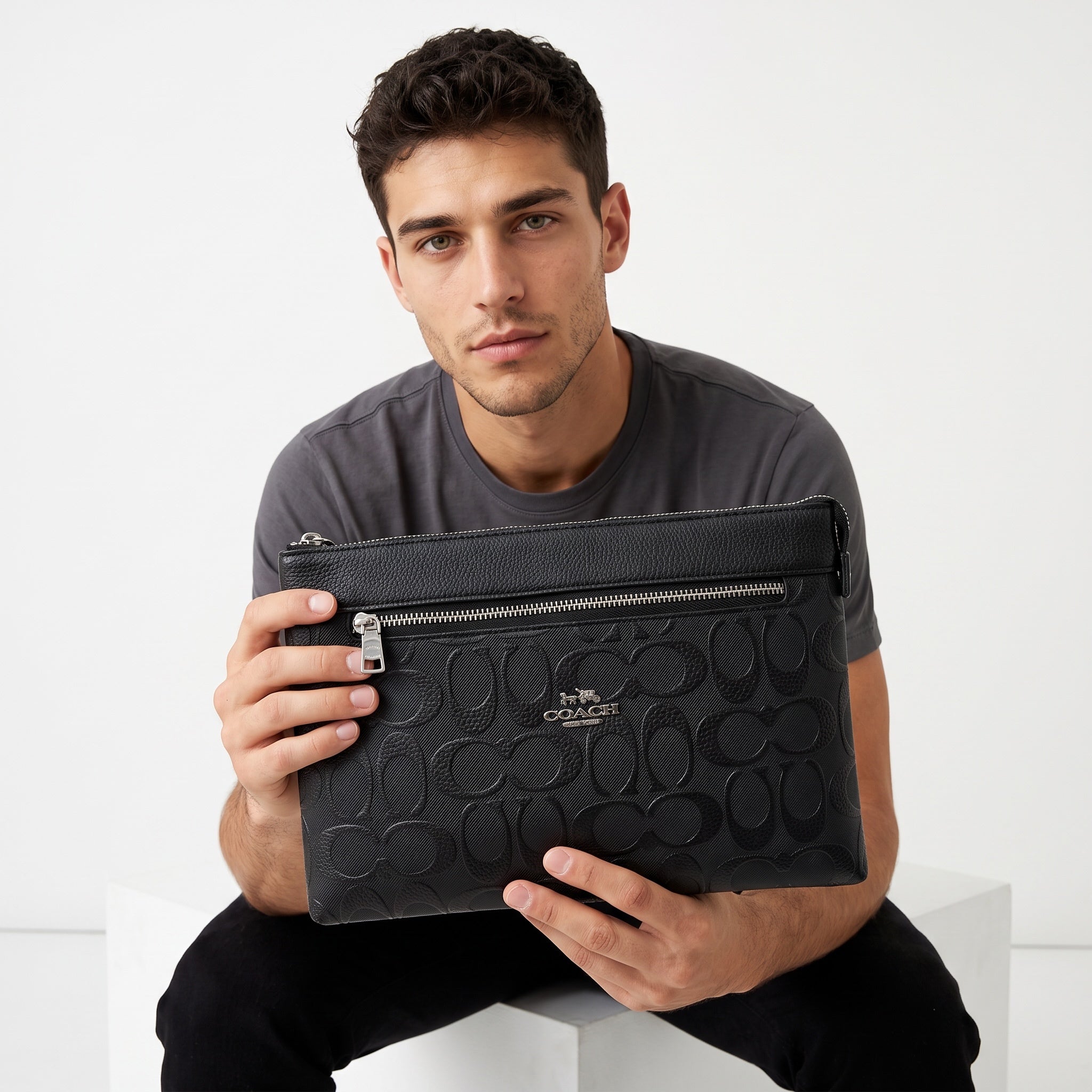 black Coach zip pouch with embossed signature pattern and silver zipper
