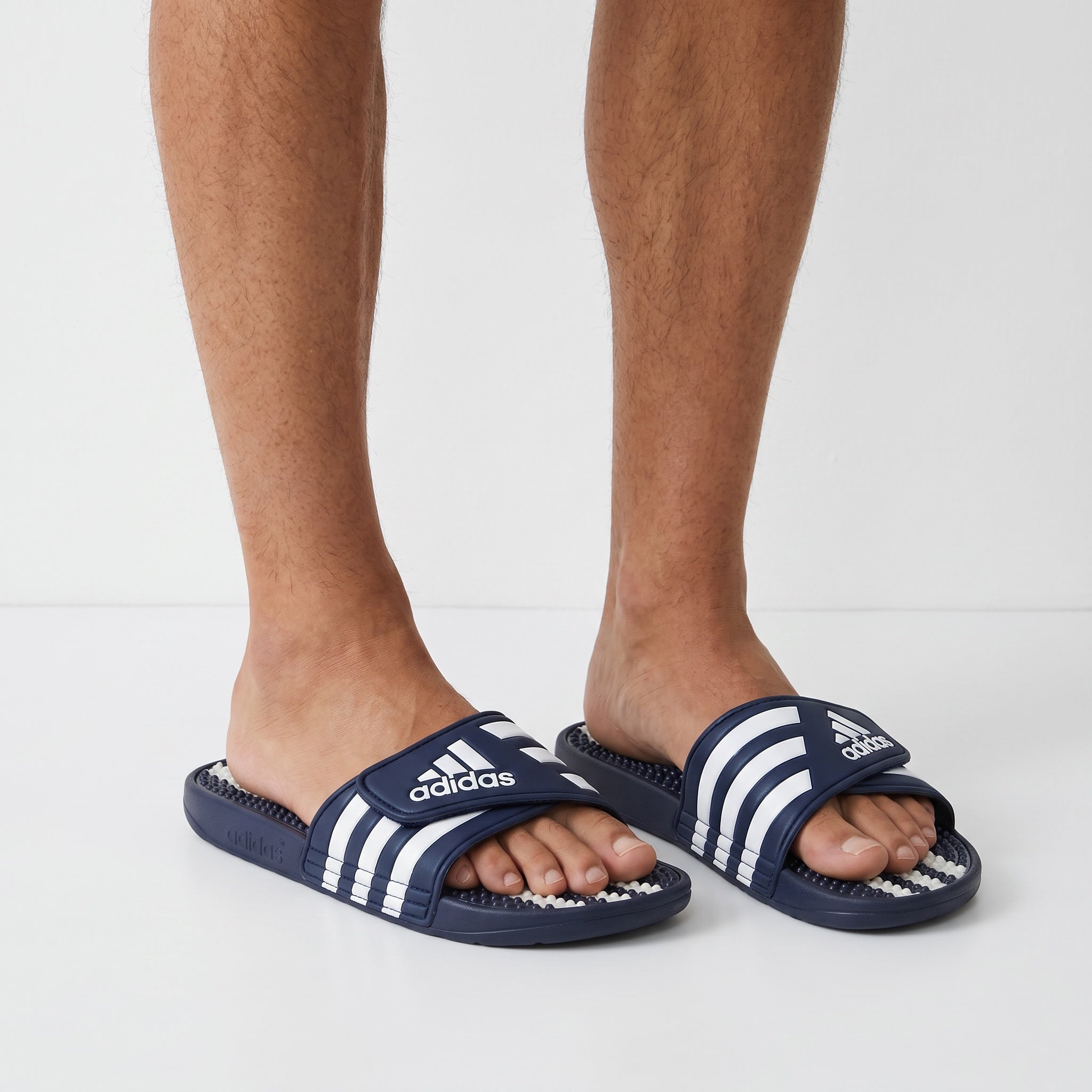 navy adidas adissage massage bead slides with white stripes on model's feet