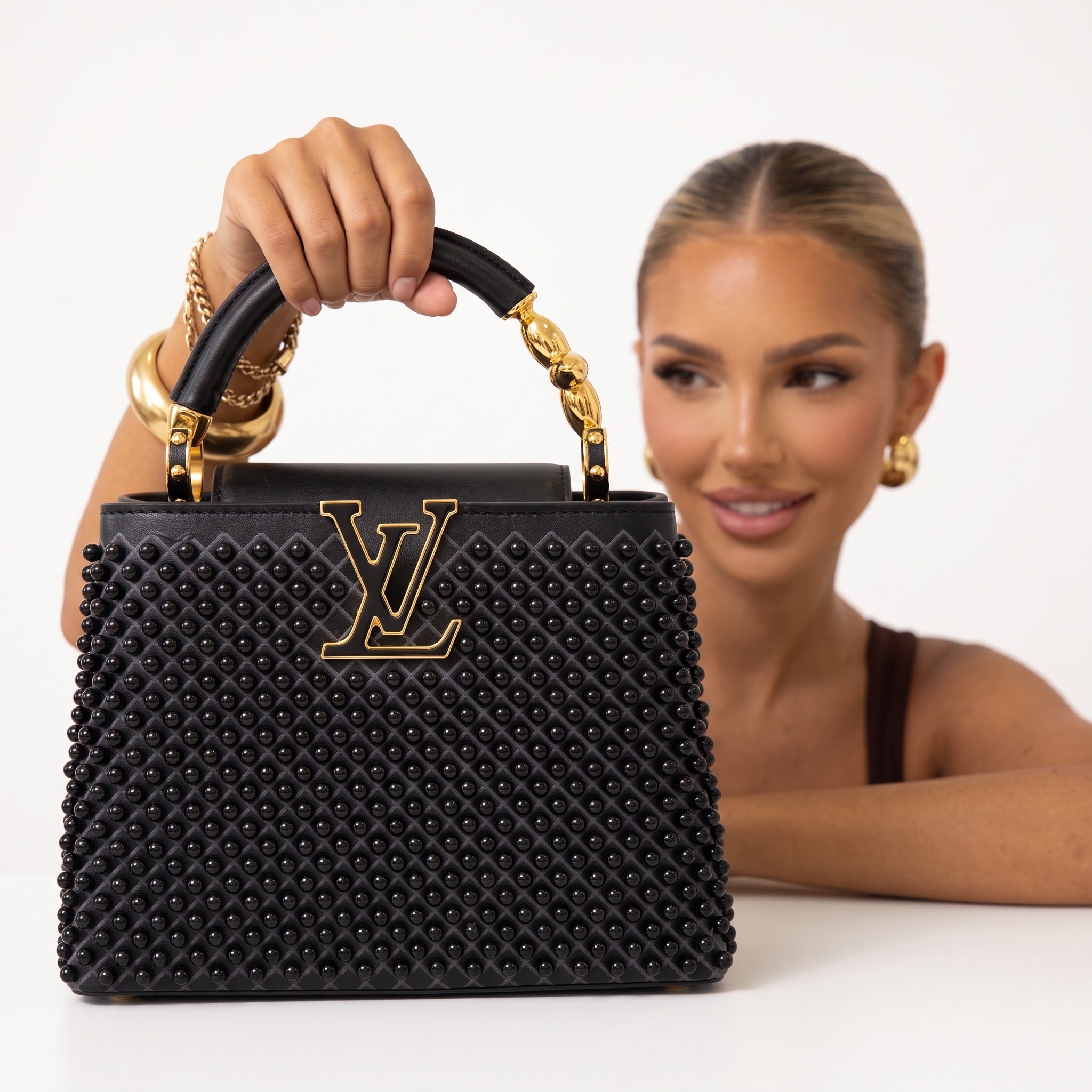 Black Louis Vuitton Capucines bag with studs and gold LV plaque, top handle visible