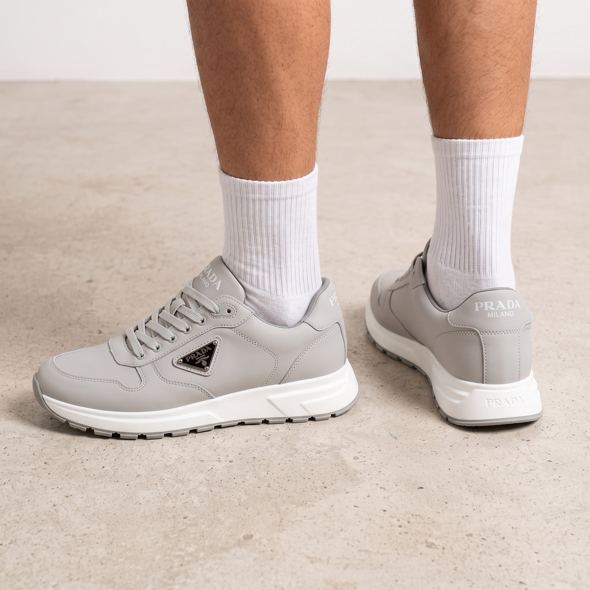Prada grey low-top sneakers with triangular logo plaque and chunky white sole