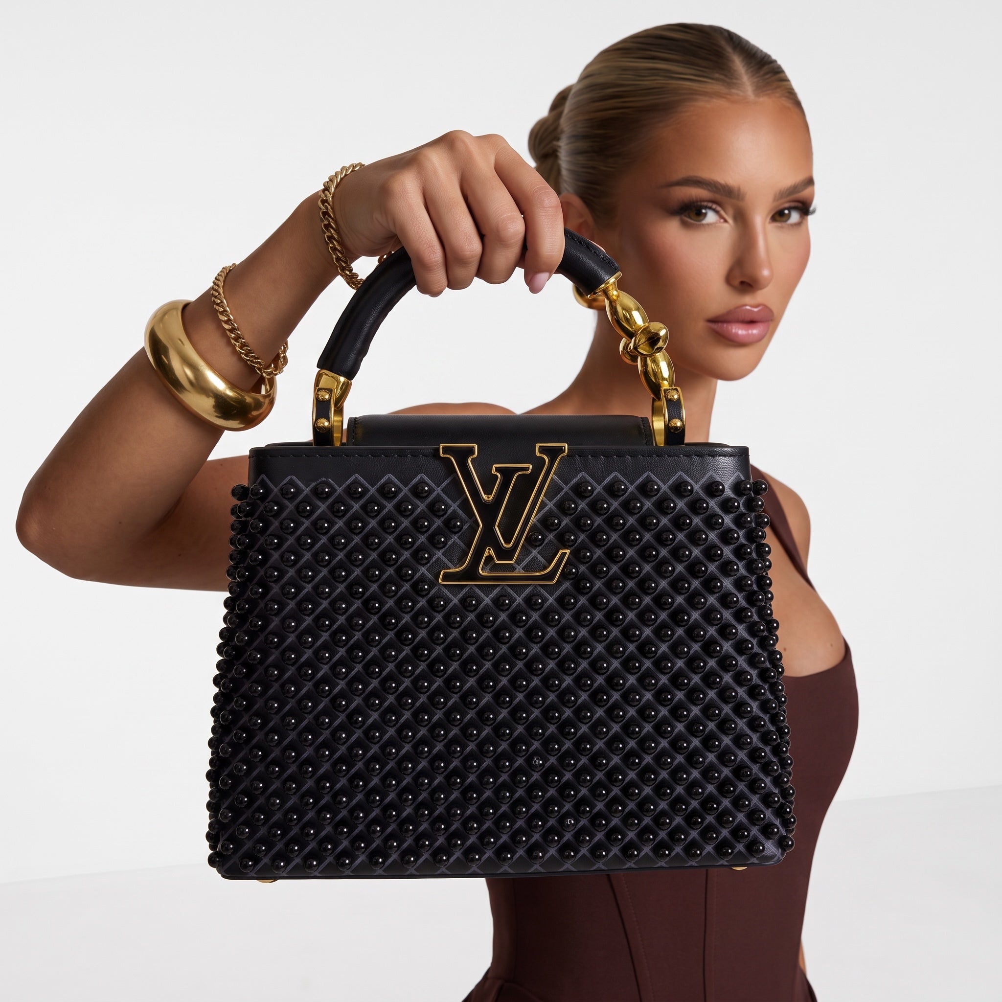 Black Louis Vuitton Capucines bag with studs and gold LV plaque, top handle visible