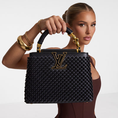 Black Louis Vuitton Capucines bag with studs and gold LV plaque, top handle visible