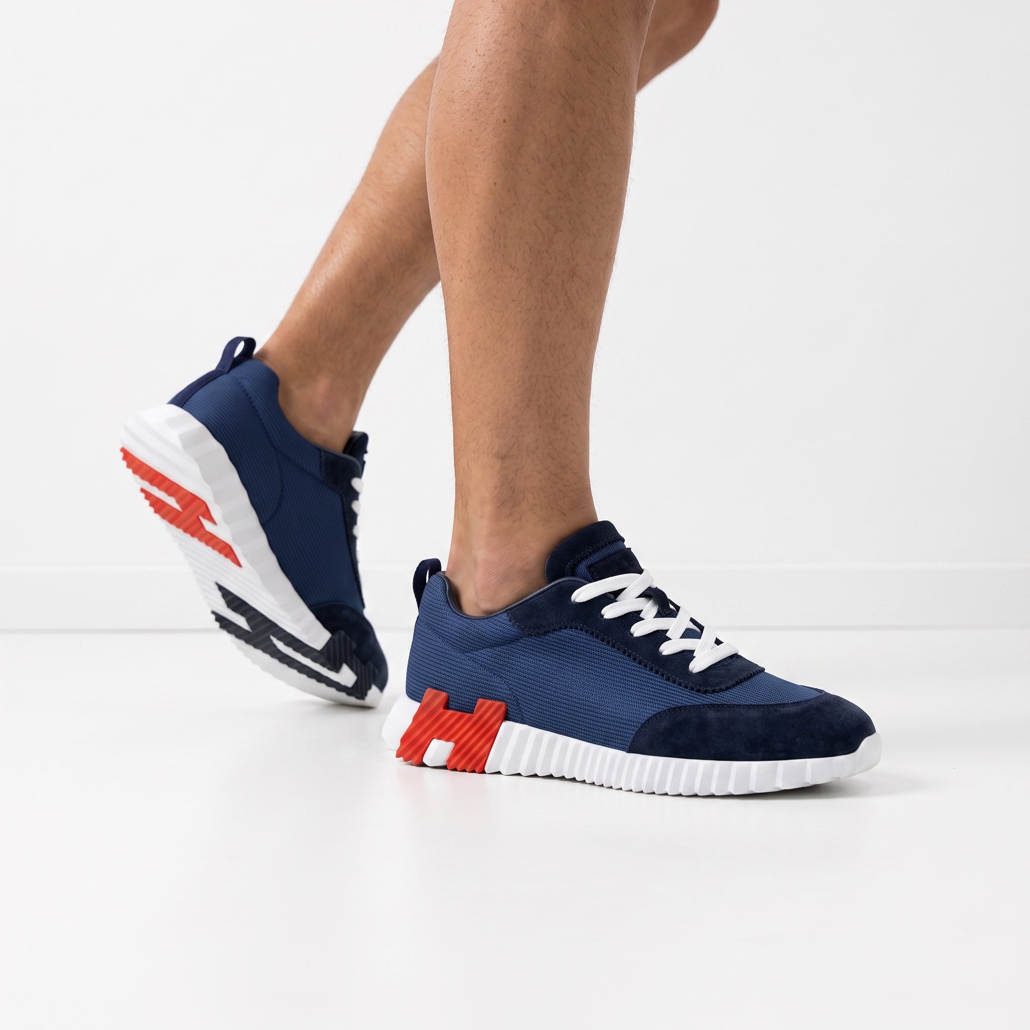 navy low-top sneakers with white sole and orange tread accents