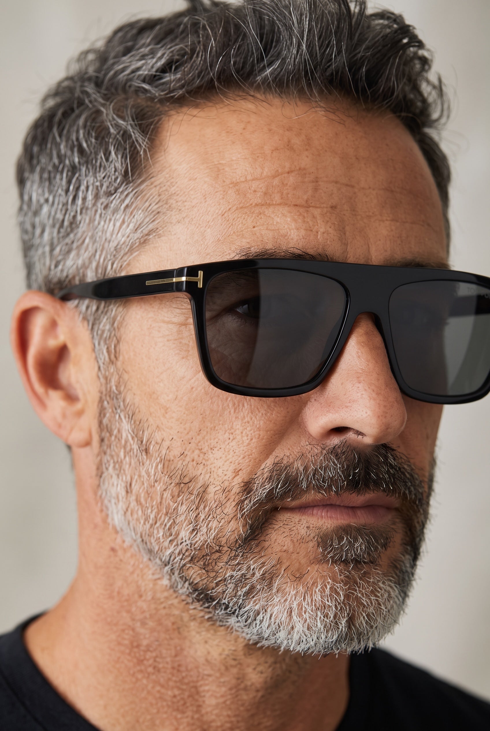 Close-up of a man wearing black Tom Ford sunglasses with gold T logo