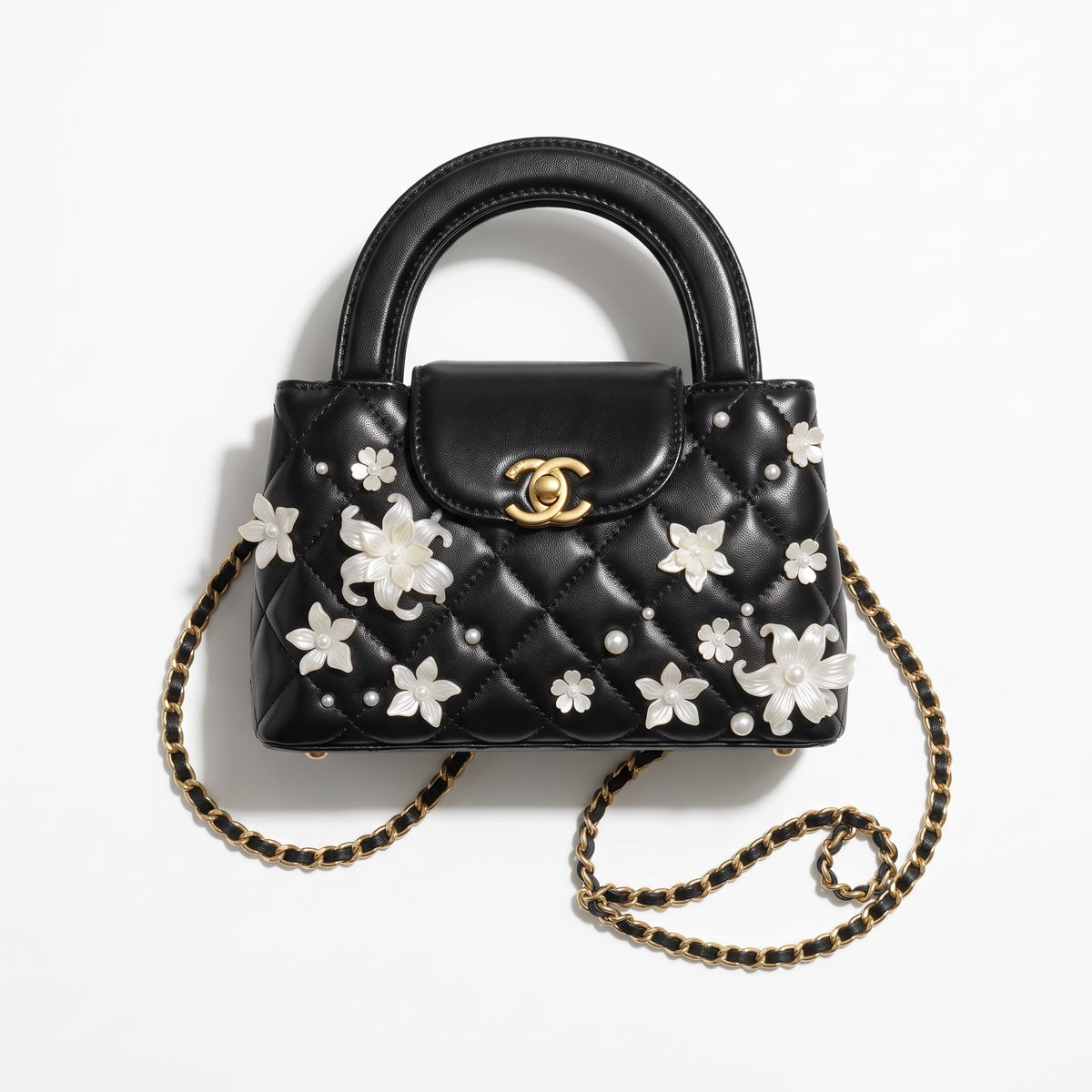 black quilted mini top-handle bag with white floral and pearl appliqués and gold chain strap