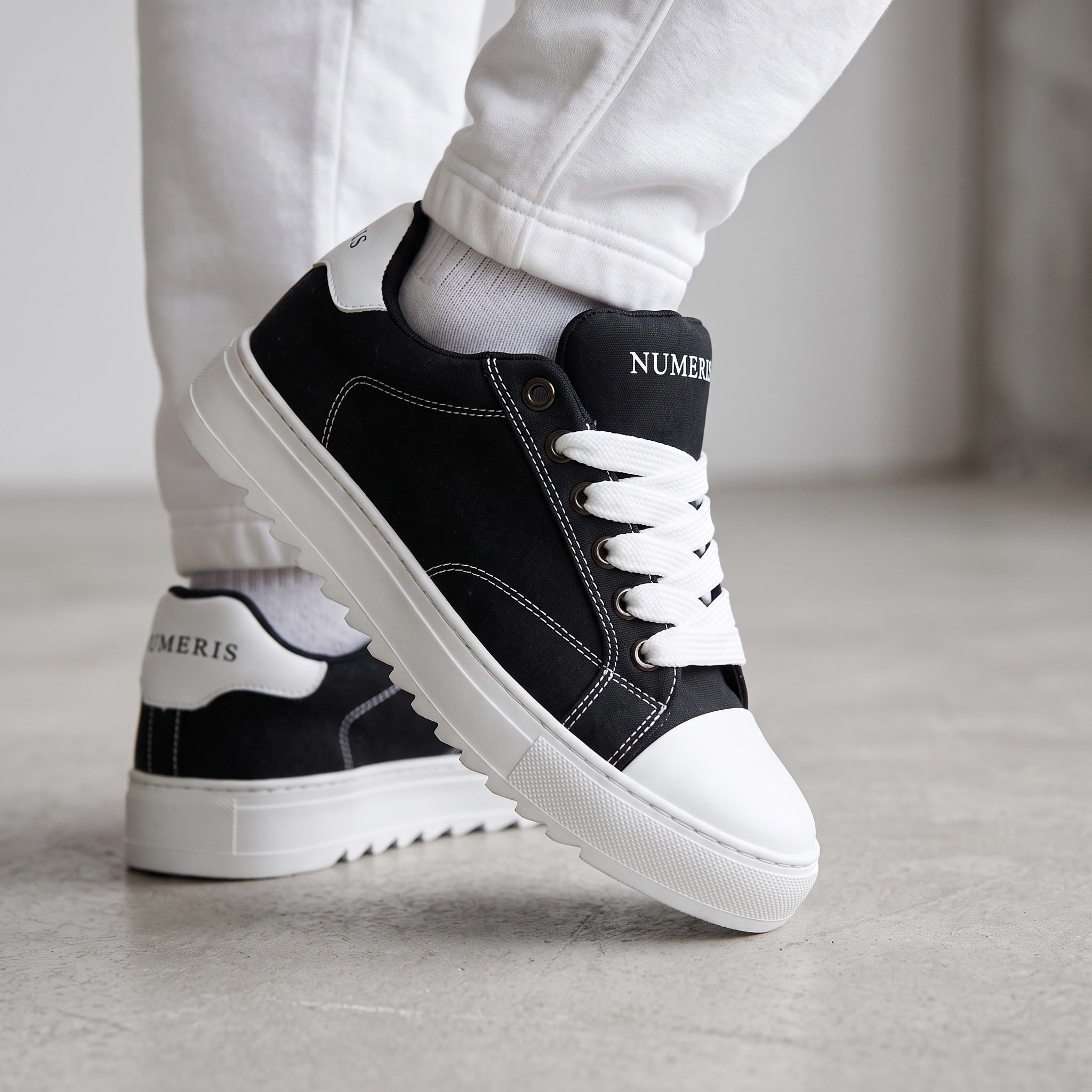 Black Numeris low-top sneakers with white laces, white toe cap and chunky ridged white sole