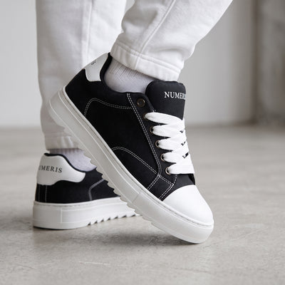 Black Numeris low-top sneakers with white laces, white toe cap and chunky ridged white sole