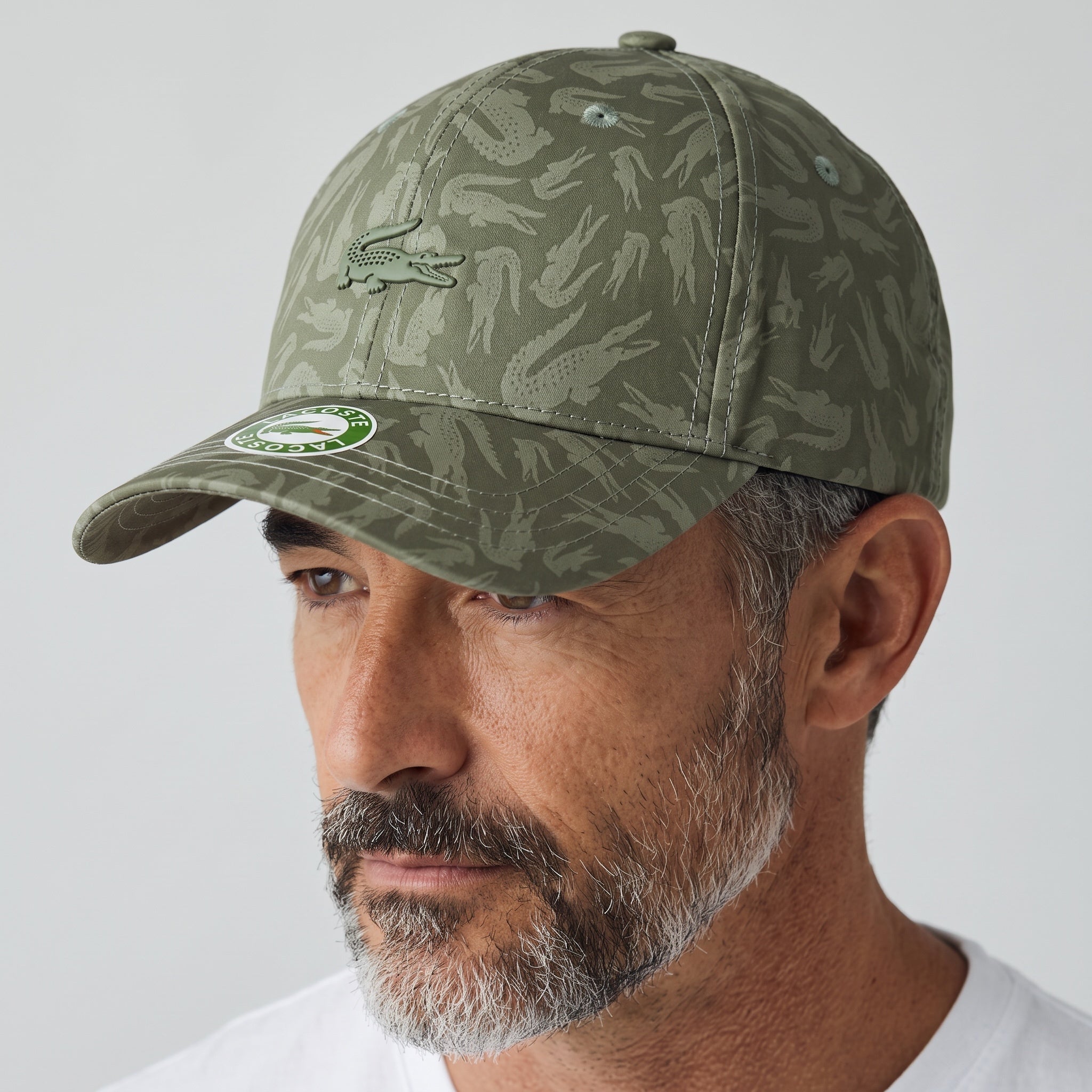 Man wearing an olive green Lacoste baseball cap with allover crocodile print