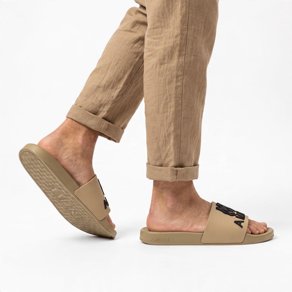 AMIRI beige rubber slides with black logo on model feet