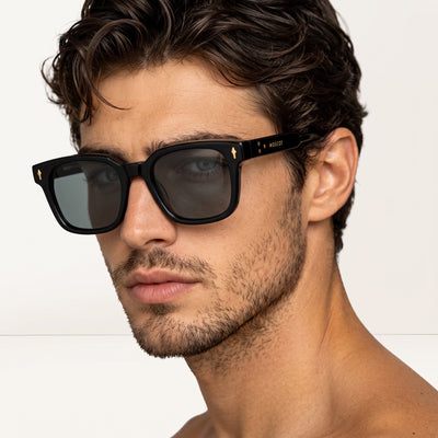 Close-up of Moscot black square sunglasses with gold logo on temple