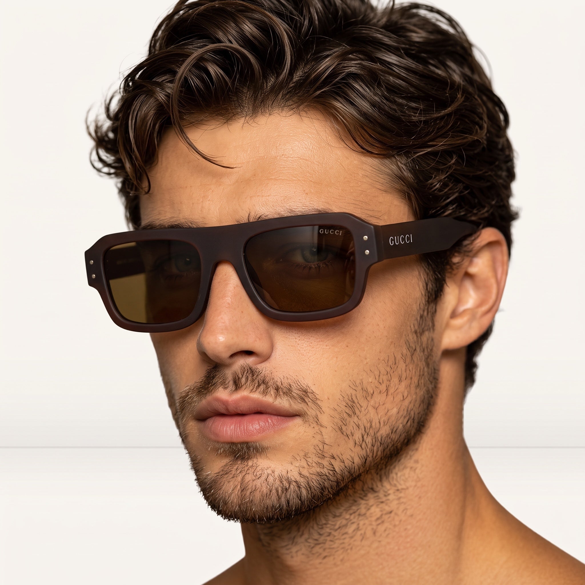Close-up of man wearing Gucci matte brown square sunglasses showing GUCCI logo on temple