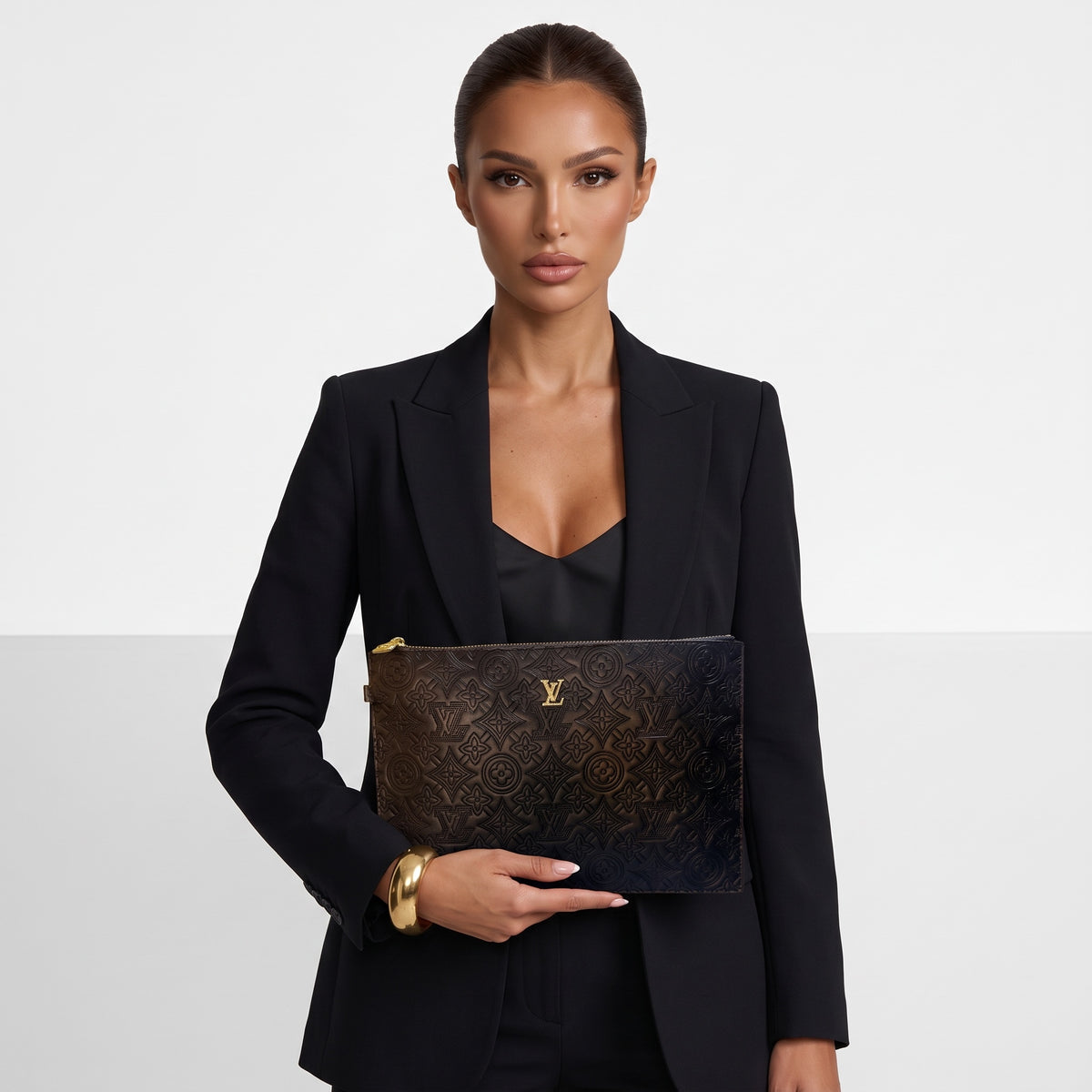 Louis Vuitton black embossed monogram flat pouch with gold zipper held by model