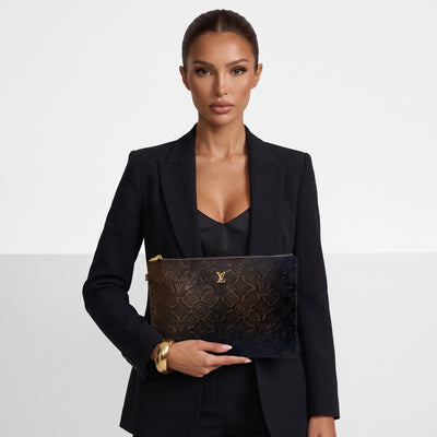 Louis Vuitton black embossed monogram flat pouch with gold zipper held by model