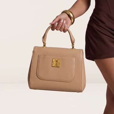 Beige top-handle bag with gold hardware and decorative charms