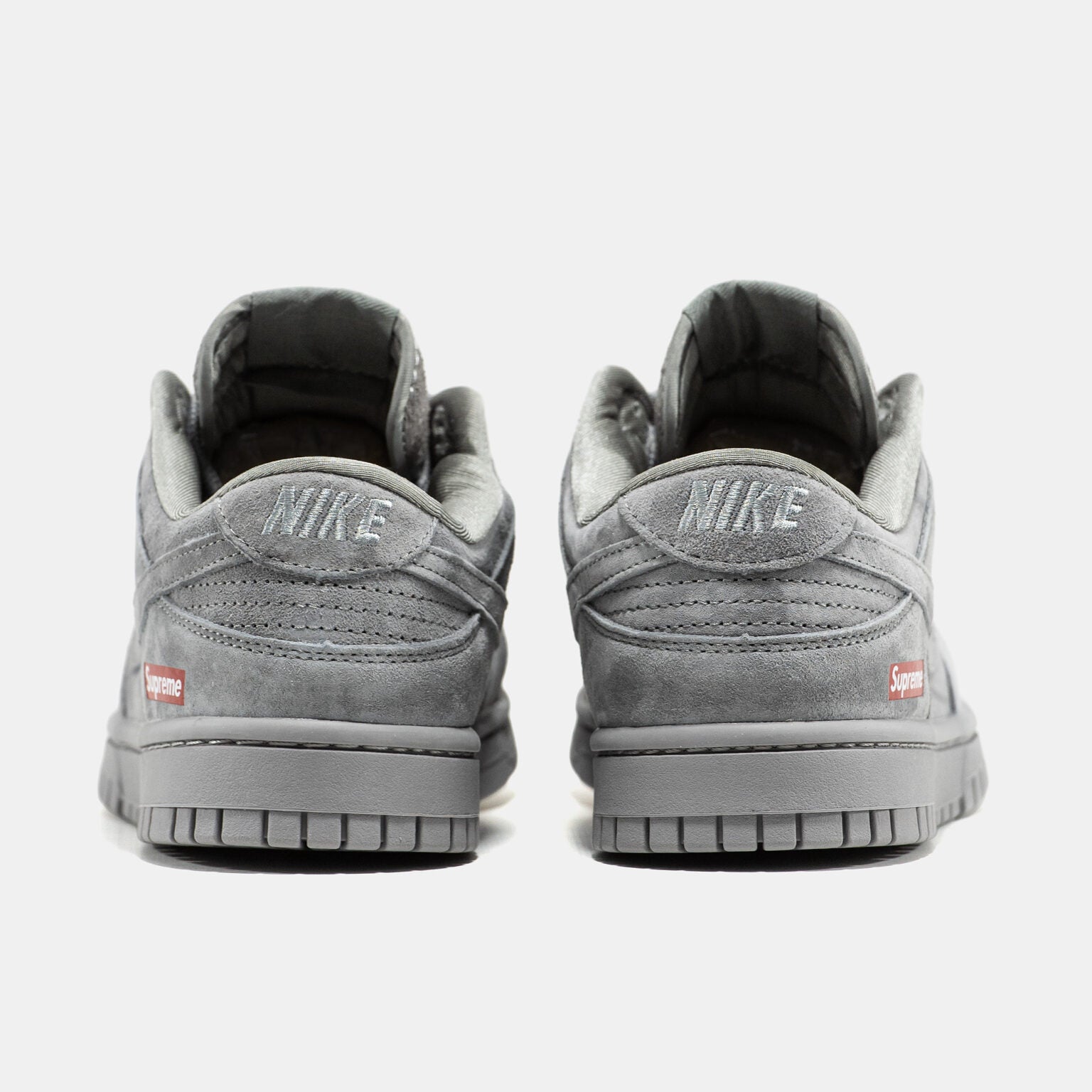 Grey Nike Dunk Low suede sneaker with small red Supreme box logo at heel