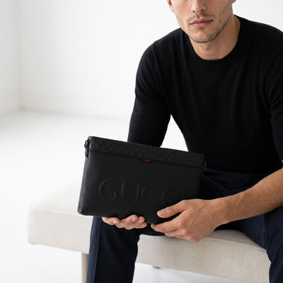 Black Gucci embossed logo pouch with GG motif and green-red tab