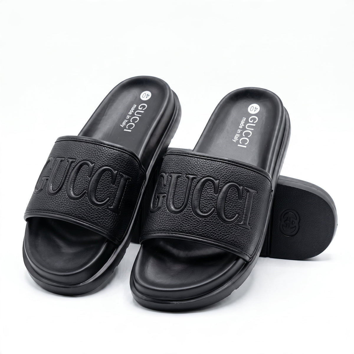 Pair of black Gucci embossed logo slides showing footbeds and strap texture