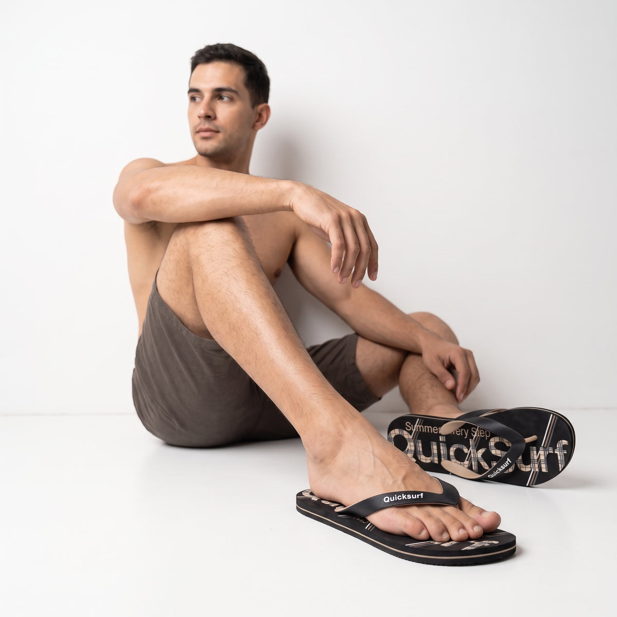 black Quicksurf flip flops with beige plaid printed footbed