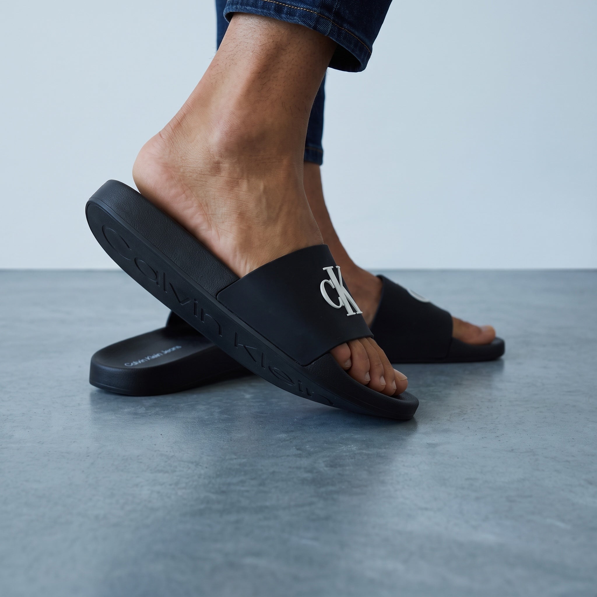 Black Calvin Klein men's slide sandals with raised CK logo