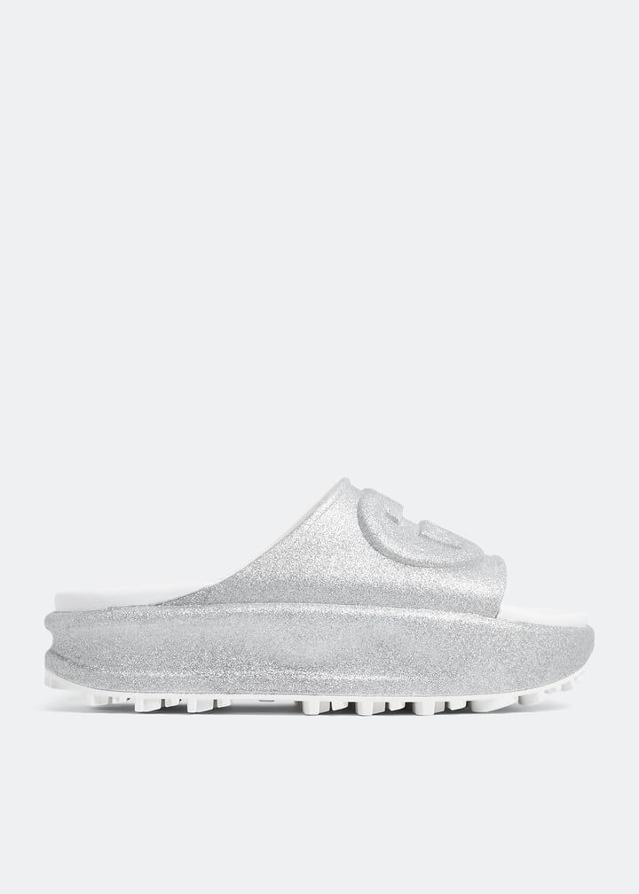Silver Gucci flatform slides with glitter finish and raised interlocking G logo on white footbed