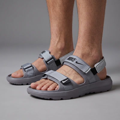 Grey Nike strappy sport sandals with adjustable webbing straps on model feet