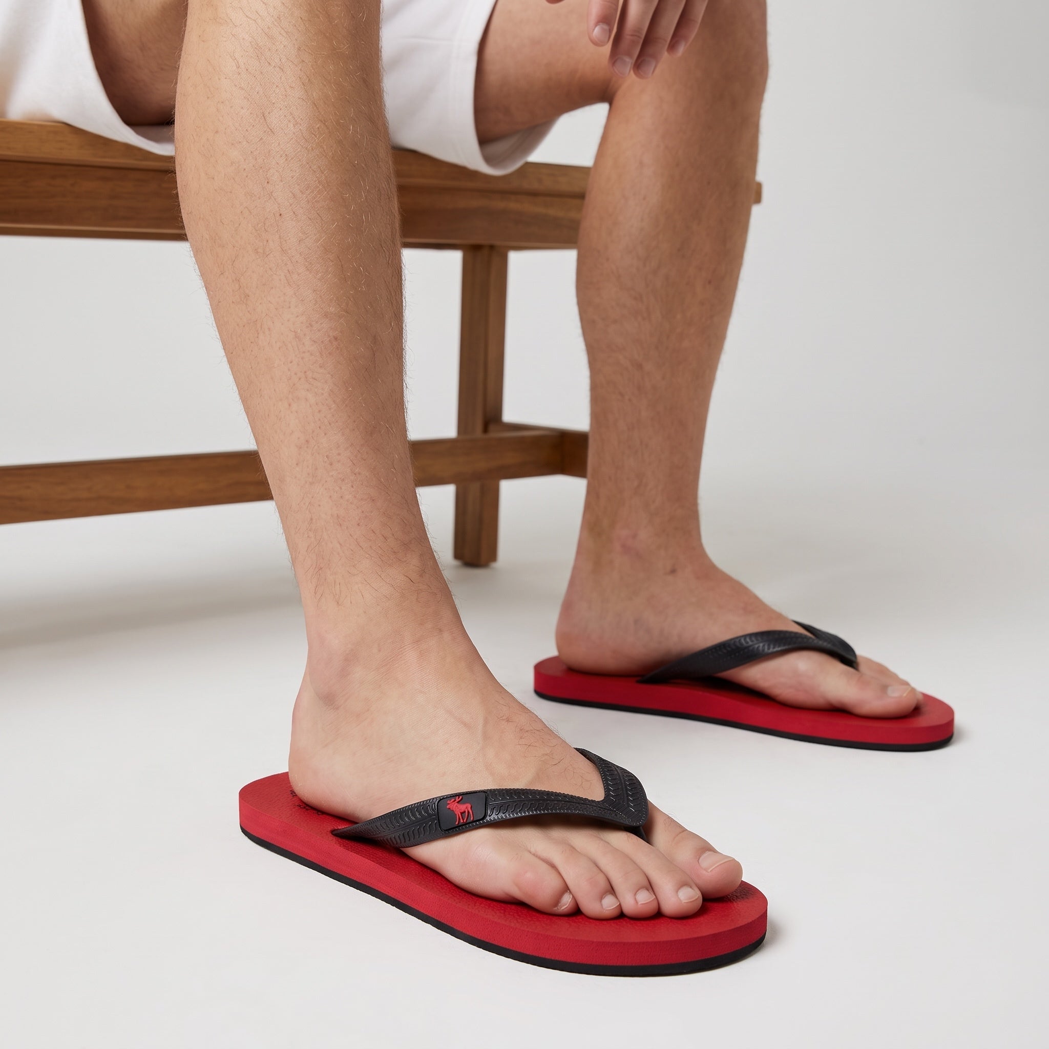 red sole flip flops with black textured straps and small red logo on strap