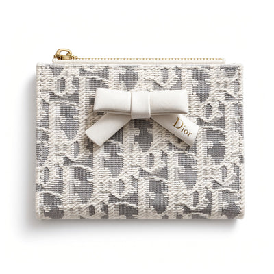 Dior compact wallet with bow and patterned exterior, open showing card slots and gold zipper