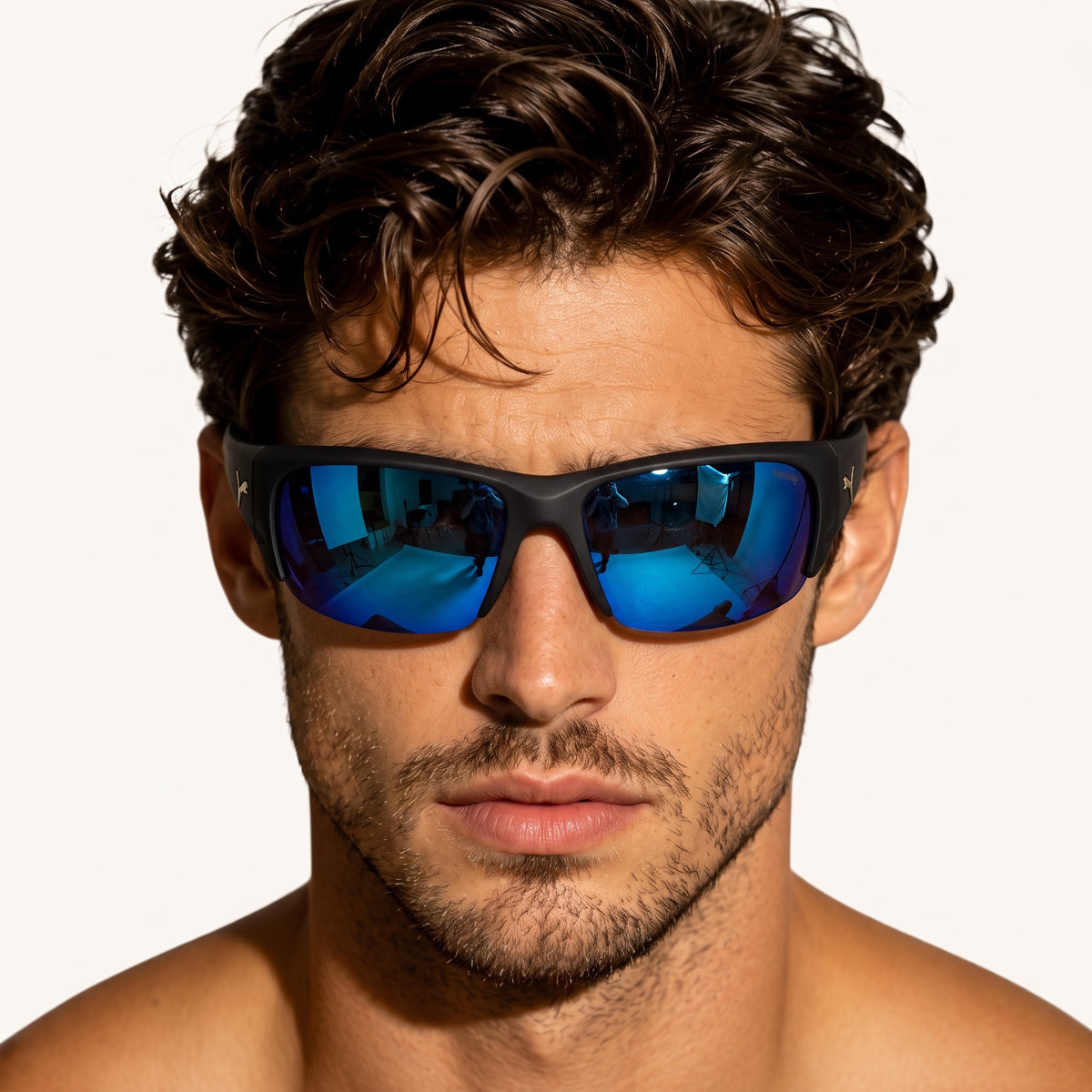 Close-up of man wearing black Puma wrap sunglasses with blue mirrored lenses