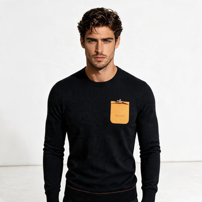 Black Hermès crewneck sweater with orange chest pocket and gold clasp
