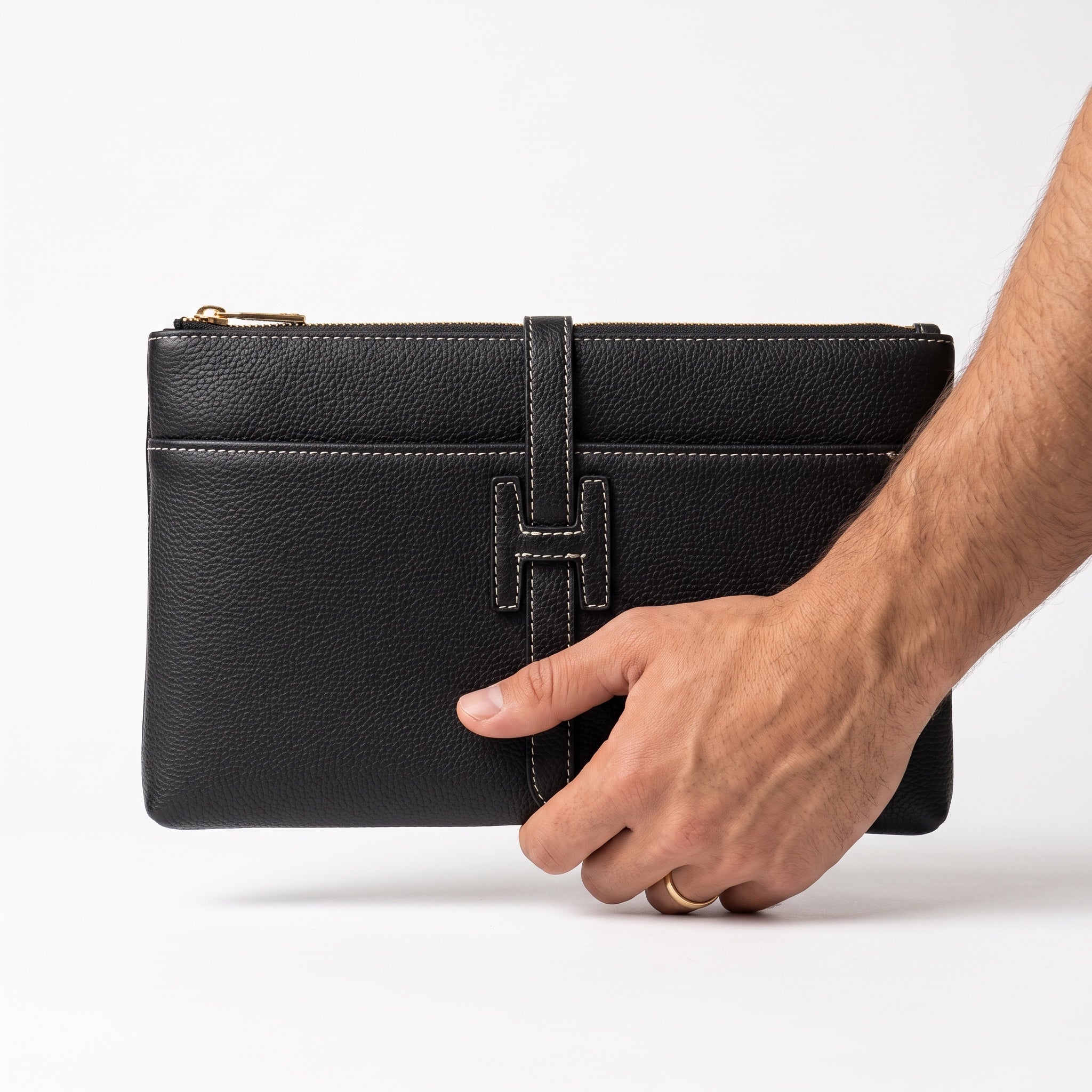 black pebbled leather Hermès clutch with white stitching and H tab detail