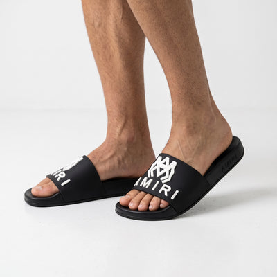 Black Amiri slide with white raised logo on strap and embossed sole