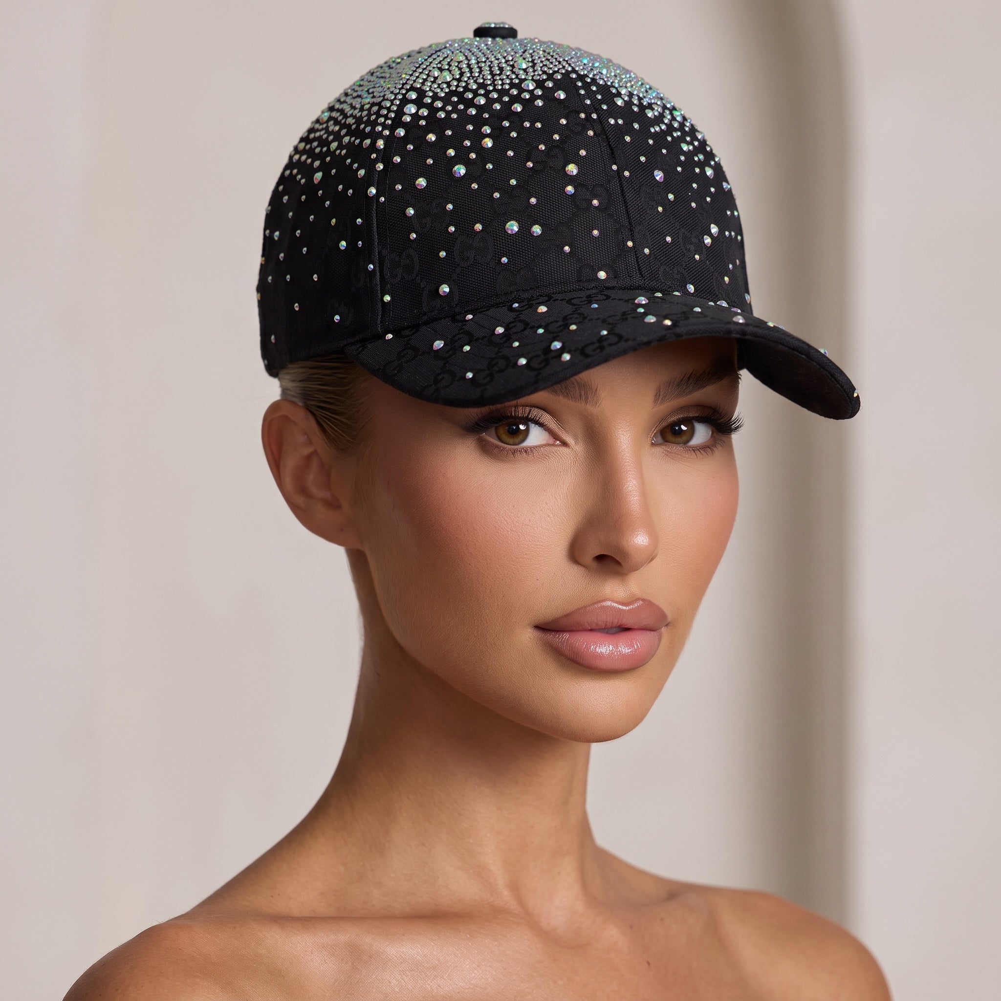 Black GG monogram baseball cap covered in iridescent crystals, worn by a model
