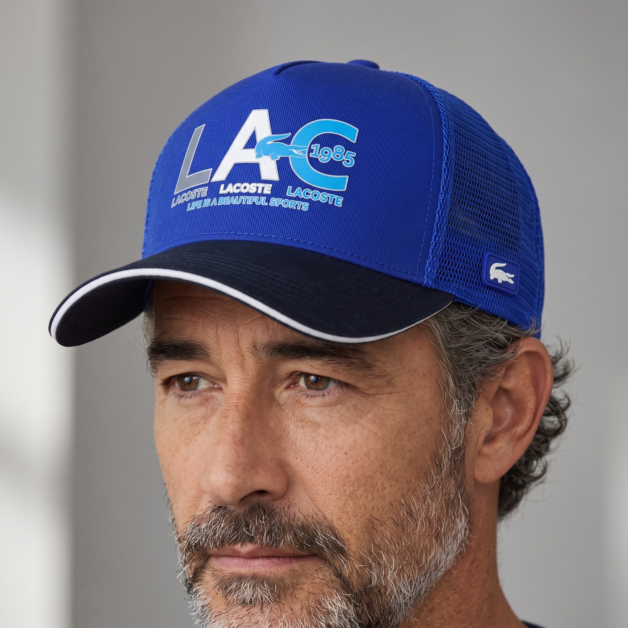 Man wearing a royal blue Lacoste LAC 1985 mesh trucker cap with navy bill