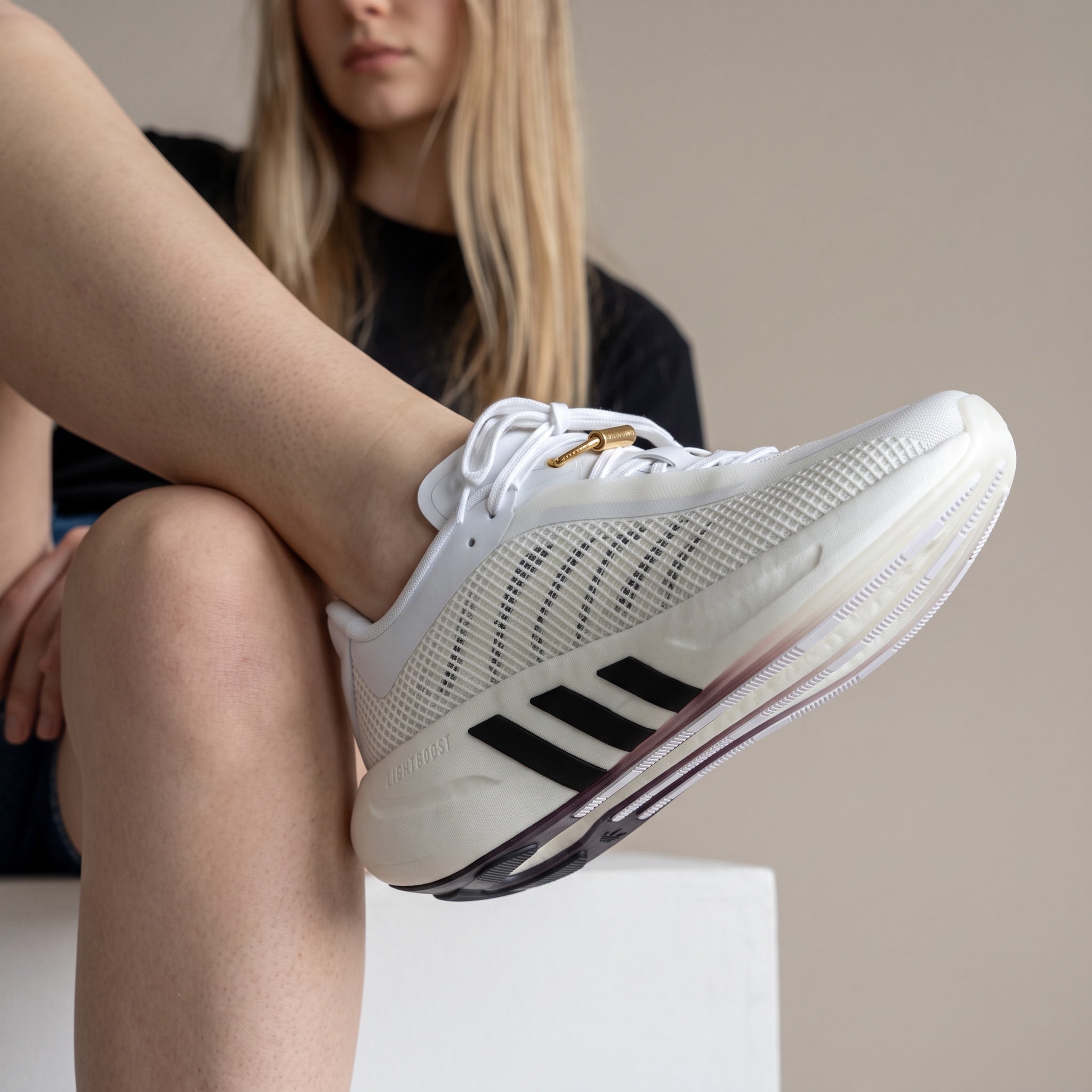 white adidas hyperboost sneaker with mesh upper and black three stripes
