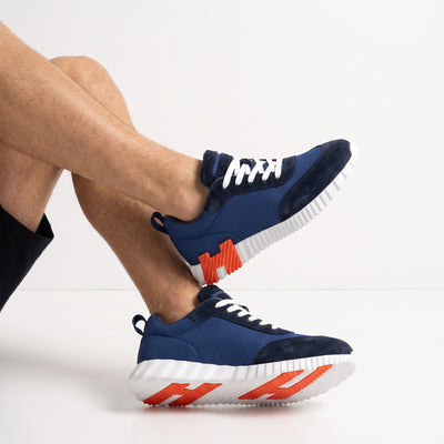 navy low-top sneakers with white sole and orange tread accents