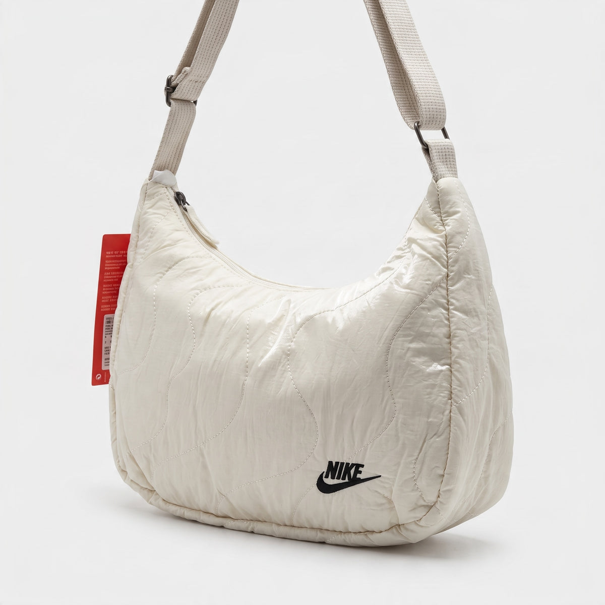 Ivory quilted Nike shoulder bag with adjustable strap and embroidered logo.