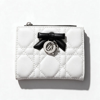 White quilted Dior compact wallet with black bow charm and black interior card slots