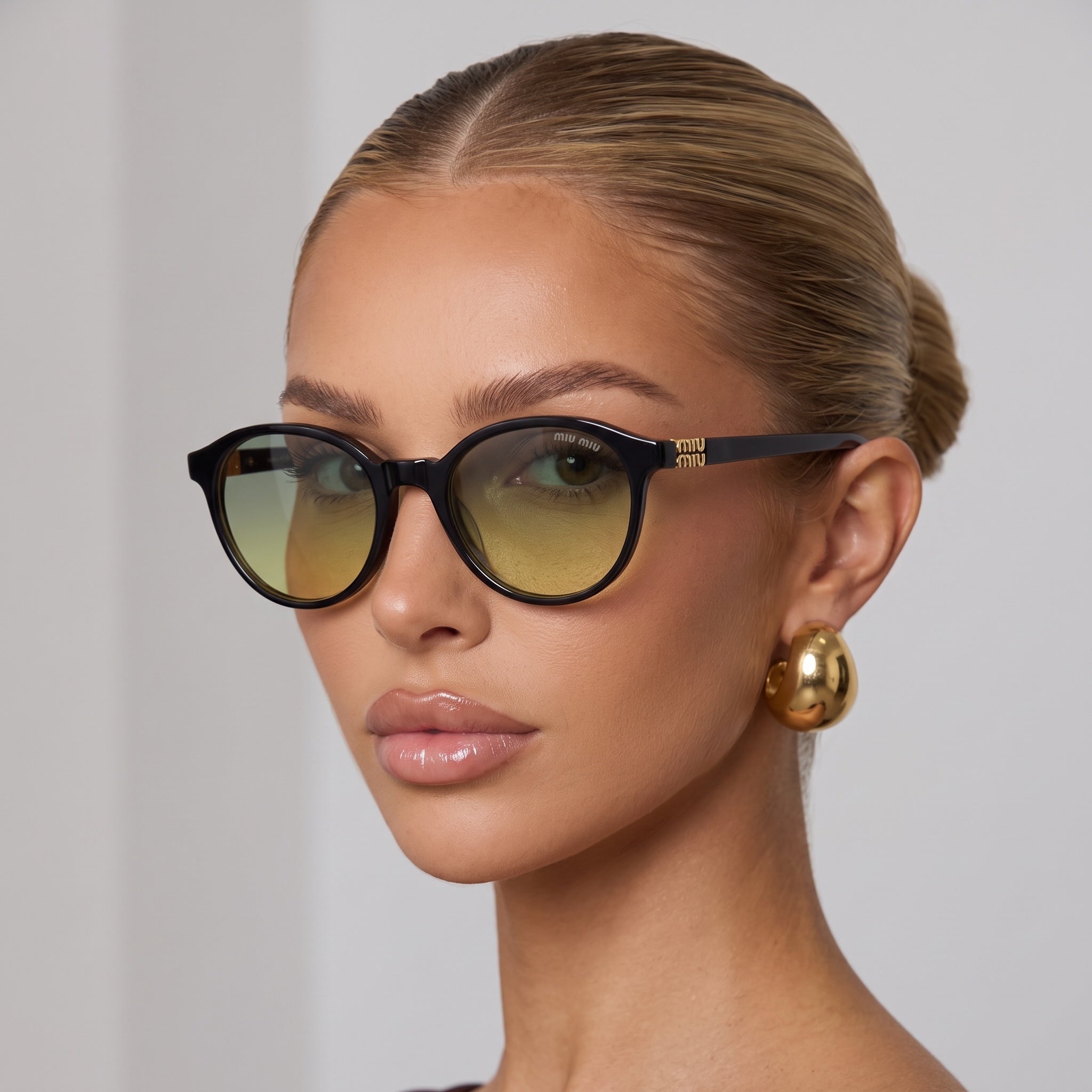 Miu Miu cat-eye sunglasses with black frame and green-yellow gradient lenses