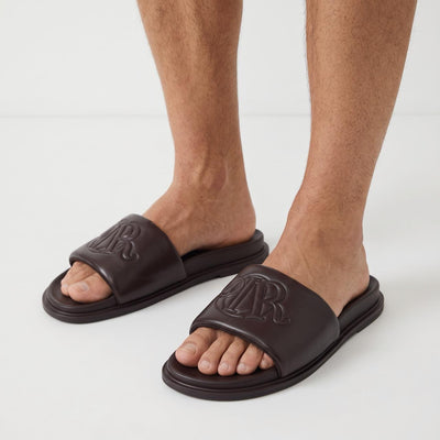 Dior dark brown padded slide sandals with embossed monogram on foot
