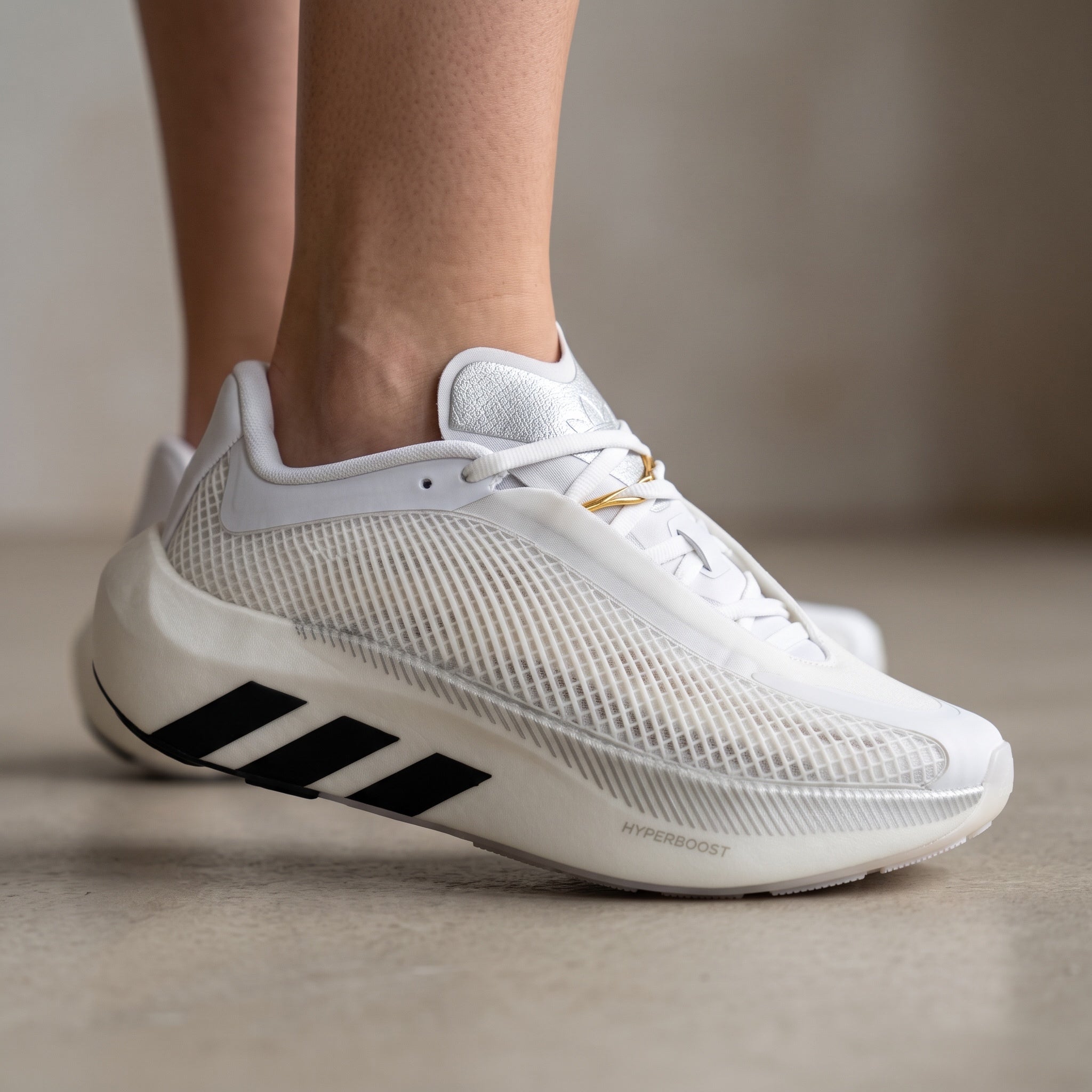white adidas hyperboost sneaker with mesh upper and black three stripes